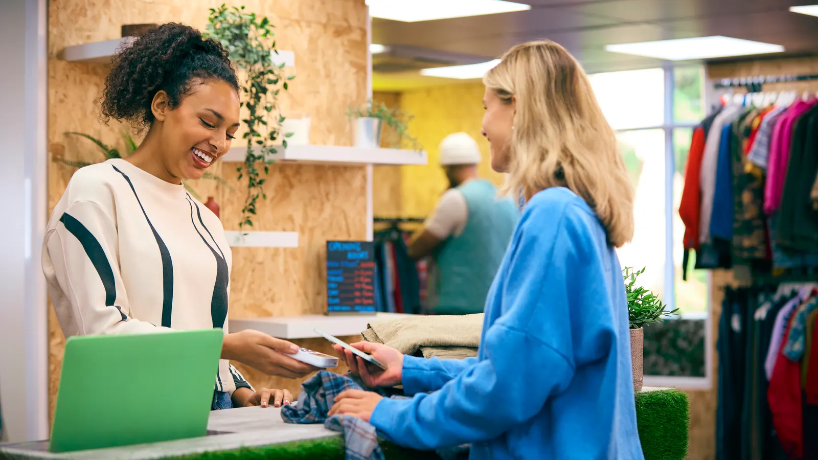 A shop owner ringing up a smiling customer at the counter